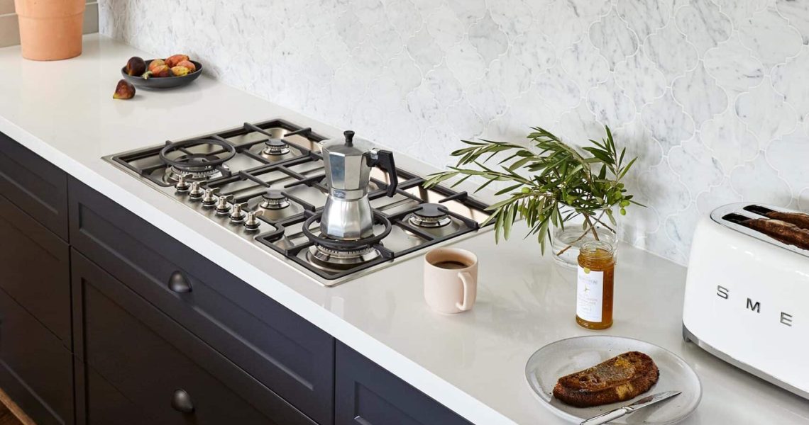 dark blue kitchen with white work surfaces
